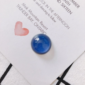 Vista macro di una perla di vetro blu scuro lucida su un cartoncino da regalo