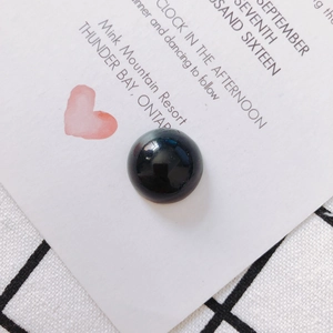 Macro di una perla in vetro nero lucido su un cartoncino bianco con motivo a cuore