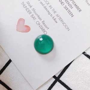 Macro di una perla in vetro smeraldo lucido per la creazione di gioielli su carta decorata