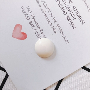 Macro detail of a creamy white resin semi-round bead on vintage stationery background