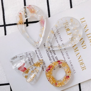 Dettaglio di ciondoli in resina trasparente con foglia d'oro e petali di fiori essiccati