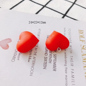 Close-up of red heart resin earring charms with metal loops on a grid background