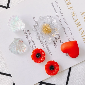 Flat lay of colorful acrylic charms including sunflower, heart and shell for DIY jewelry