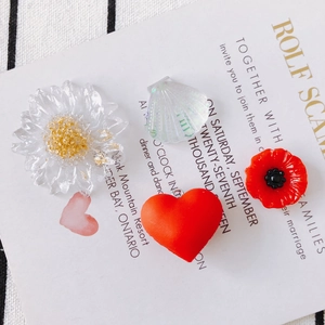 Macro view of clear daisy, heart, and shell acrylic charms for DIY earring accessories