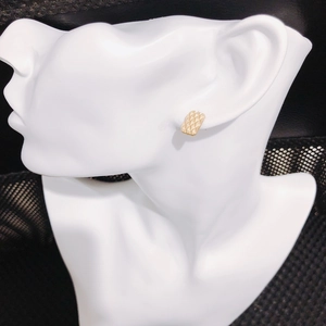 Detail view of golden rectangular earring with waffle pattern on a white model