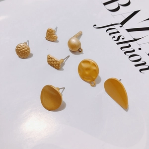 Macro detail of matte gold alloy earring studs in heart, square and geometric shapes