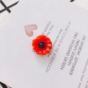 Macro shot of red acrylic flower charm with black center on a white card background