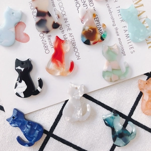 Détail macro de breloques chat en acrylique coloré avec motifs variés et trous pour le DIY