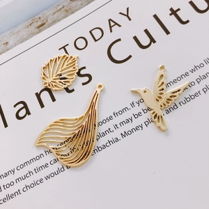 Detailansicht der goldenen Anhänger in Form von Blättern, Federn und Kolibris für DIY