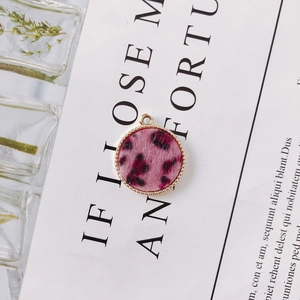 Macro detail of round leopard print pendant with gold micro-bead trim and plush texture