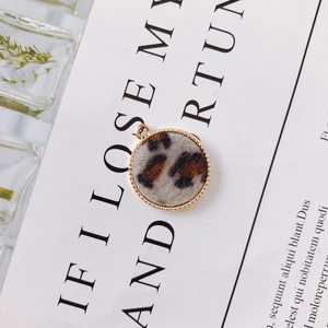 Macro detail of round leopard print earring pendant with golden beaded metal frame for DIY