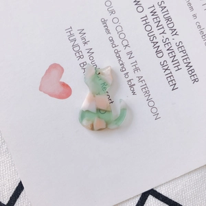 Vue macro d'un pendentif chat en acrylique marbré vert et rose pour boucles DIY