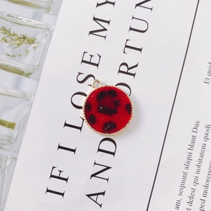 Detailed view of red leopard print round pendant with textured gold metallic border