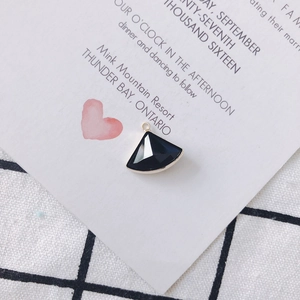 Détail macro d'un pendentif en forme d'éventail avec pierre noire et cadre en métal doré