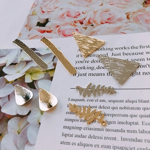 Gros plan détaillé de breloques de bijoux DIY texturées en or et argent aux formes variées