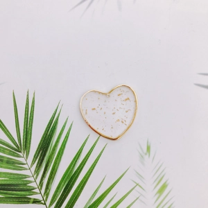 Dettaglio del ciondolo a cuore per orecchini con cornice dorata e resina con scaglie d'oro