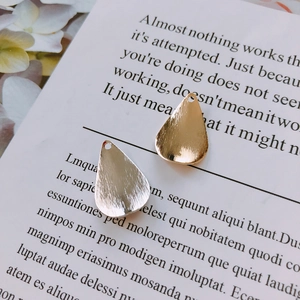 Gros plan de pendentifs goutte en métal doré et argenté avec une texture brossée fine