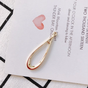 Close-up of polished gold teardrop charms with loop connectors on a creative background