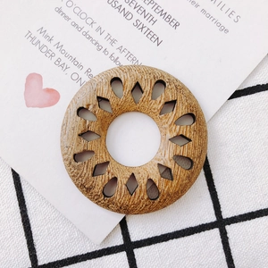 Close-up of geometric hollow wooden earring pendant with natural brown textures