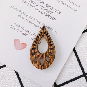 Detail view of hollow teardrop wooden earring accessory with natural grain and cutouts