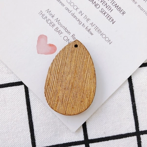 Macro view of teardrop-shaped wooden earring pendants with natural grain and pre-drilled holes