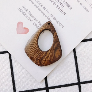 Macro shot of dark brown teardrop wood pendant with natural grain for DIY jewelry
