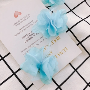 Detail of light blue 3D chiffon lace flowers on a grid tablecloth for DIY sewing accessories