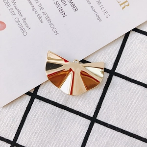 Makroansicht eines goldfarbenen fächerförmigen Plissee-Anhängers mit Loch für DIY-Schmuck