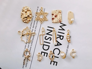 Detaillierte Flachbildaufnahme goldener Legierungsanhänger und Kunstperlen für DIY-Schmuck
