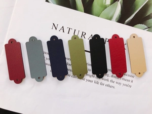 Dettaglio di etichette in pelle rettangolari in 7 colori con fori per cucito