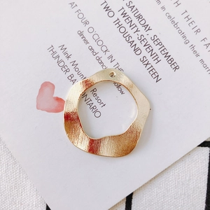 Close-up of golden irregular round pendant with vertical brushed metal texture for DIY jewelry