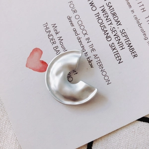 Detailed view of matte silver C-shaped geometric pendant with irregular wave texture