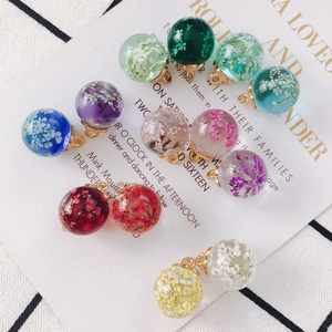 Macro shot of colorful preserved flower glass ball charms with golden metal loops