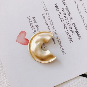 Detail of matte gold hollow C-shaped earring charm with textured rippled finish