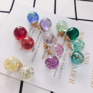 Macro shot of twelve assorted colored glass ball pendants with dried flowers and gold loops