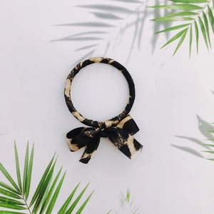 Detail of leopard print hair tie with bow ornament and textured fabric finish