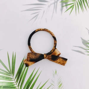 Detailed view of leopard print bow hair scrunchie with elastic band on white background