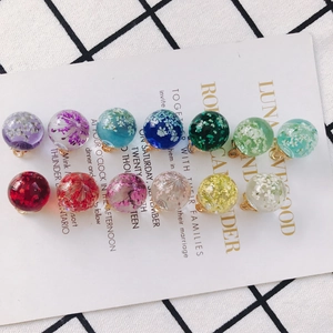 Detailed view of clear glass bead charms with colorful dried flowers and gold loops
