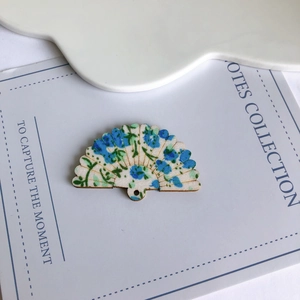 Dettaglio di ciondoli in legno a ventaglio con motivi floreali blu per gioielli e artigianato