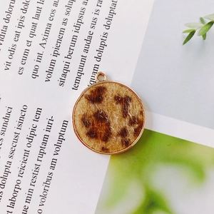 Macro view of a circular leopard print pendant with gold metal trim for DIY jewelry