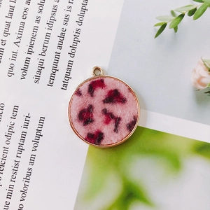 Macro detail of a round pink leopard print charm with gold metal frame for DIY jewelry