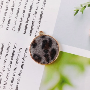 Detail view of round leopard print jewelry charm with gold metal frame and hanging loop