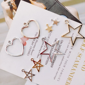Flat lay of geometric star and heart metal pendants in gold and silver for DIY jewelry