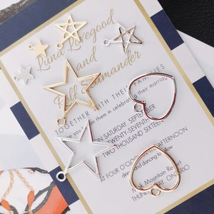 Macro detail of geometric heart and star jewelry charms for DIY earrings in gold and silver