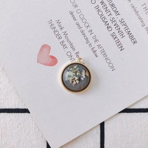 Macro shot of gold round alloy pendant with colorful shell fragments inlay and resin