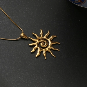 Collier doré avec pendentif soleil à spirale et rayons ondulés sur fond noir mat