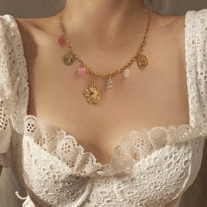 Vintage-Halskette in Gold mit Blumenanhängern und Glücksbringern, getragen von einem Model