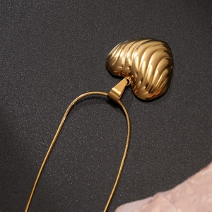 Collier cœur doré à la mode avec pendentif 3D texturé sur fond noir élégant
