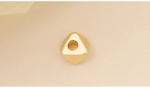 Gros plan d'une perle triangulaire dorée polie avec trou central pour bijoux DIY