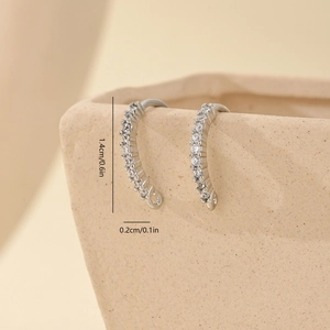 Macro shot of silver zircon curved earrings hooks with size specs on ceramic vase